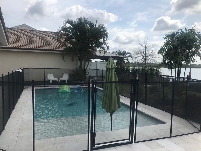 Mesh pool gate facing a rectangular pool and closed green umbrella