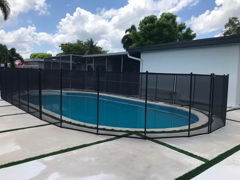 Removable mesh barriers following a curved pool beside a white house