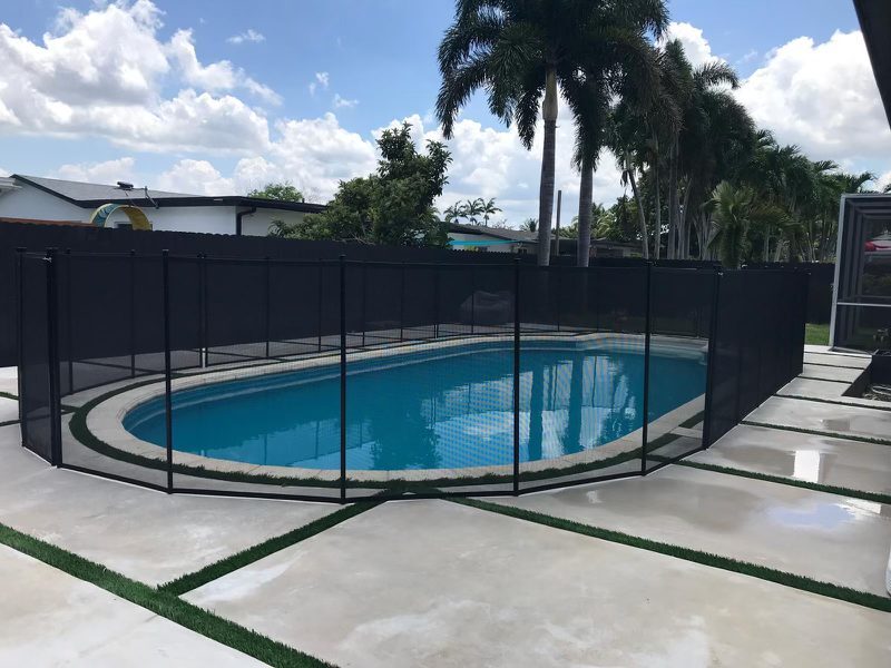 Mesh fence following a curved pool beside a deck with green accent strips