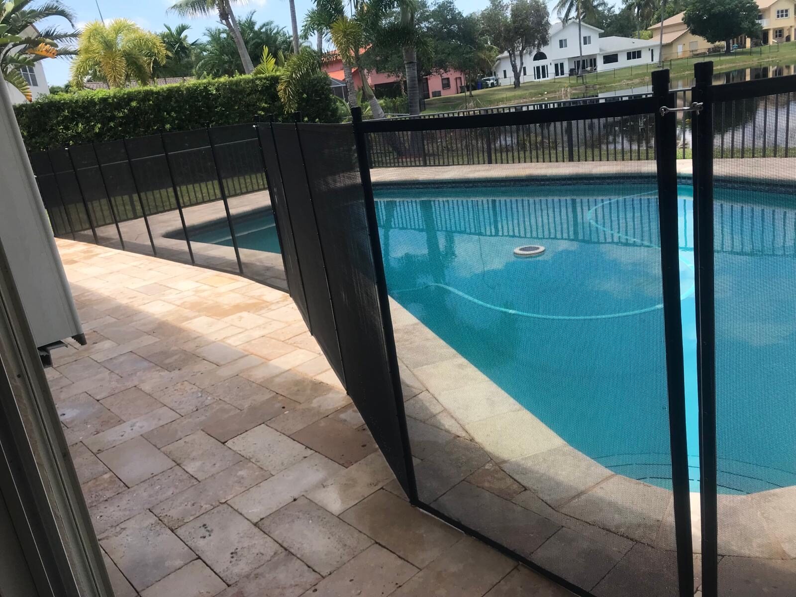 Mesh pool fence sections and connection hardware beside a blue pool