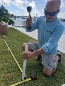 John installing a removable mesh pool safety fence in the ground beside a Florida backyard pool.