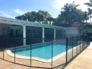 Curved black mesh pool fence surrounding a freeform pool at a Miami home.
