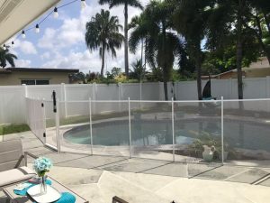 White mesh pool fence and gate across a curved backyard pool
