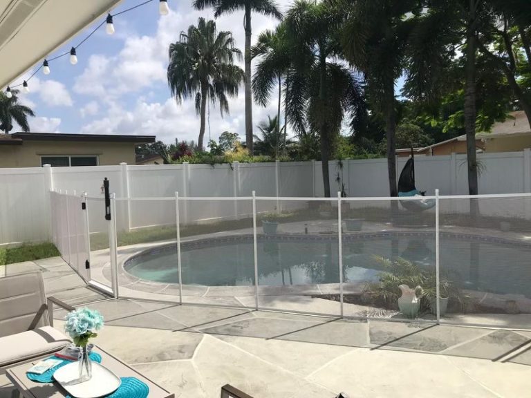 White mesh pool fence and gate across a curved backyard pool