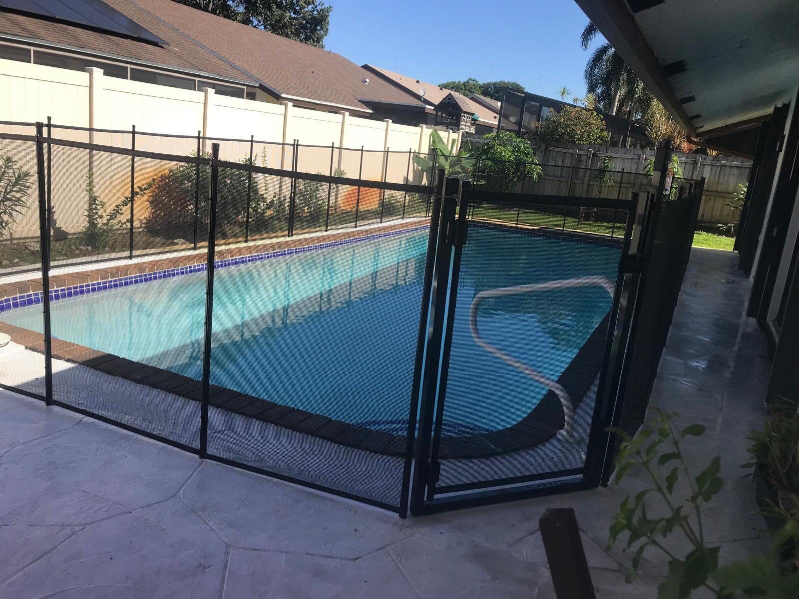 Black mesh pool gate and adjoining fence beside a narrow house-side deck