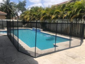 Black mesh pool fence turns around a rectangular pool on a pale stone deck