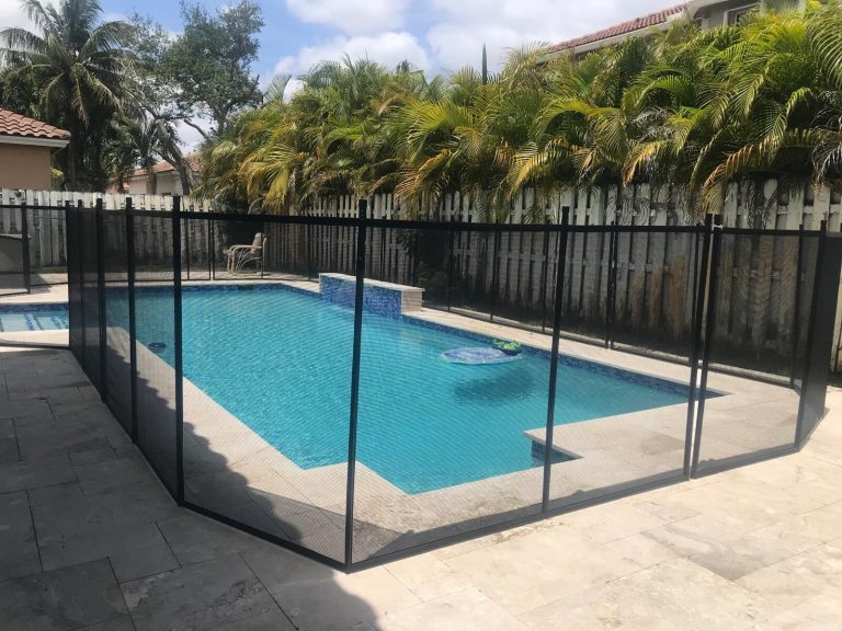Black mesh pool fence turns around a rectangular pool on a pale stone deck