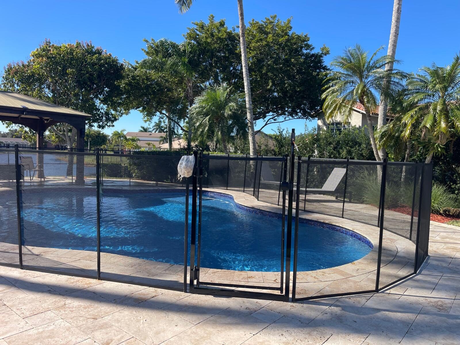 Pool service access planning: mesh fence with a central gate beside a curved Pembroke Pines pool