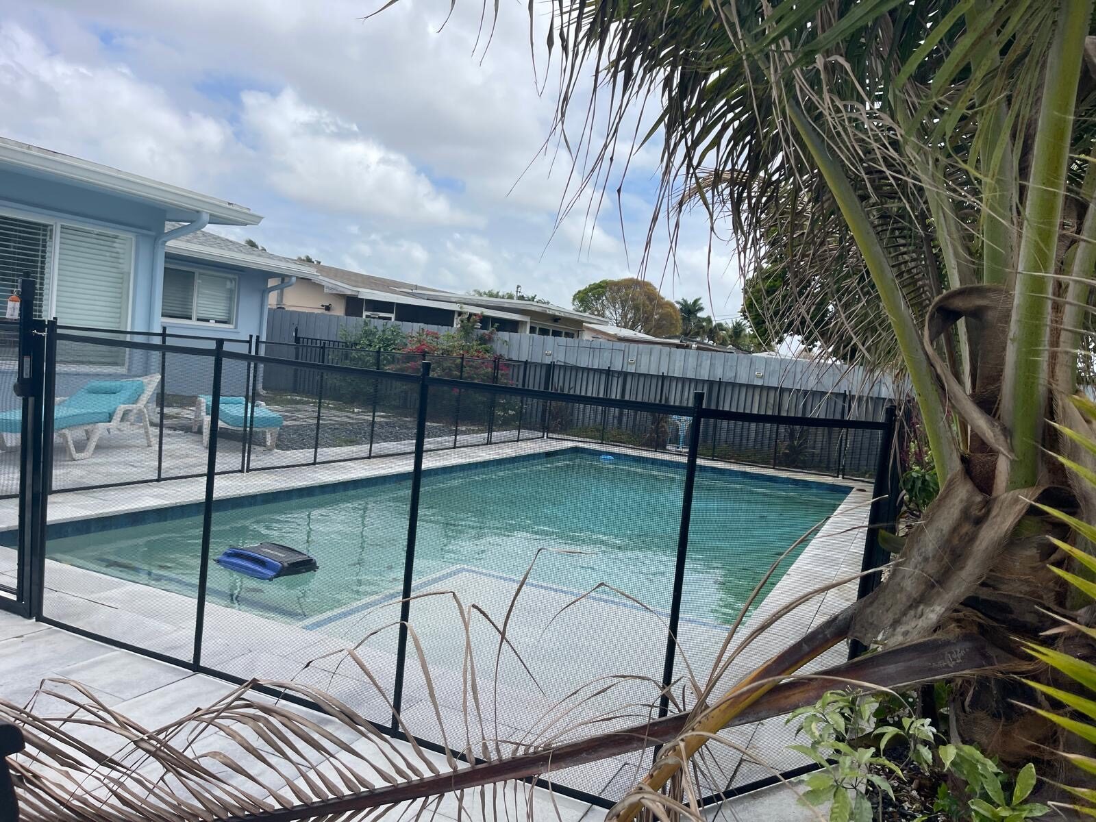 Black mesh pool fence beside a rectangular pool and palm trees in Pembroke Pines