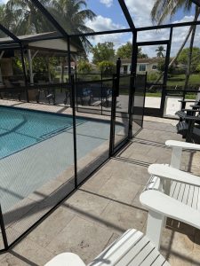 Black mesh fence and gate inside a screened Plantation pool area, illustrating the barrier layer alongside pool alarms