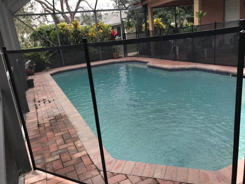 Mesh pool fence beside a brick walkway inside a screen enclosure