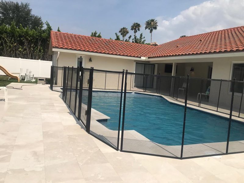Home Depot pool fence guide illustration: black mesh fence beside a pale stone patio