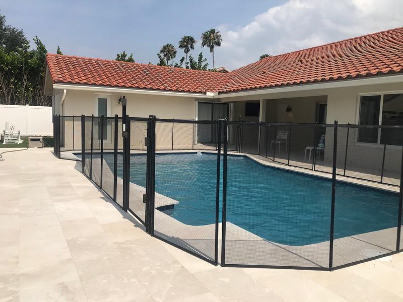 Pool fence gate and angled mesh panels beside a blue pool