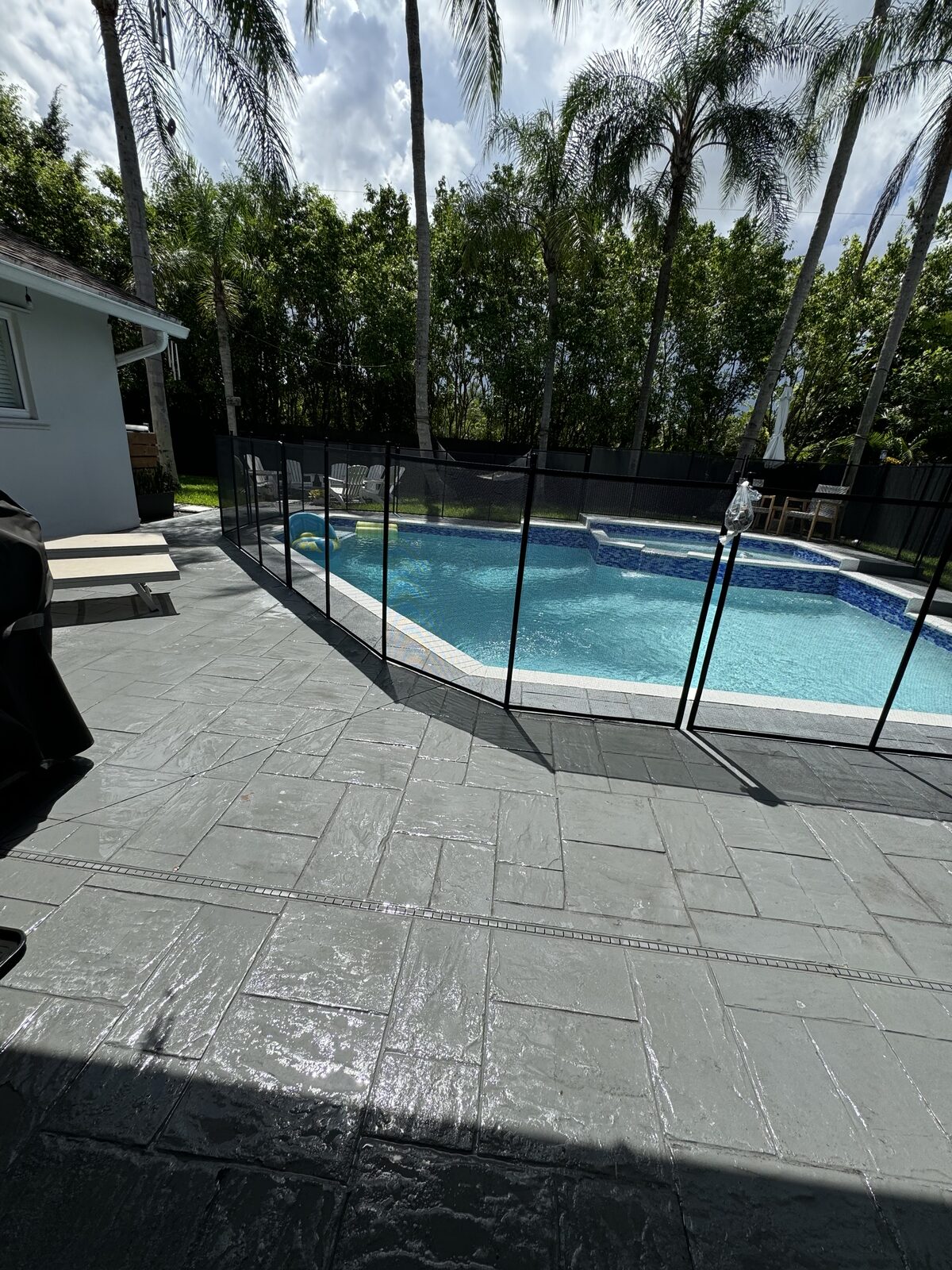 Existing pool fence sections and gate beside a gray paver deck in Plantation